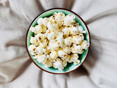 Popcorn gezond: Bovenaanzicht van een kom popcorn op een bank