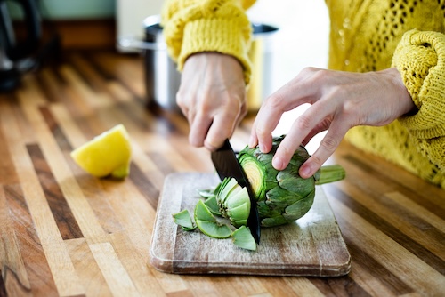 artisjok recept: Een vrouw die artisjok klaarmaakt, schoonmaakt, snijdt, afsnijdt