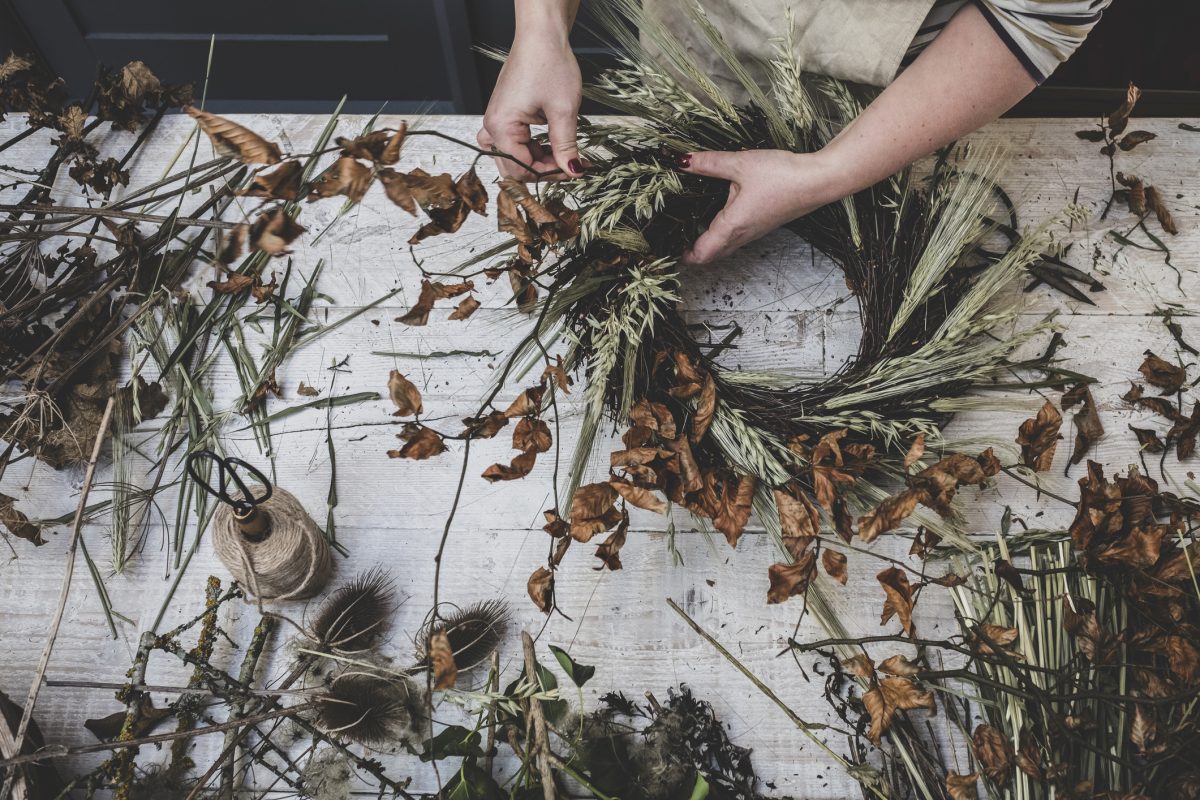 Woman Making A Small Winter Wreath Of Dried Plants, Brown Leaves And Twigs, And Seedheads.