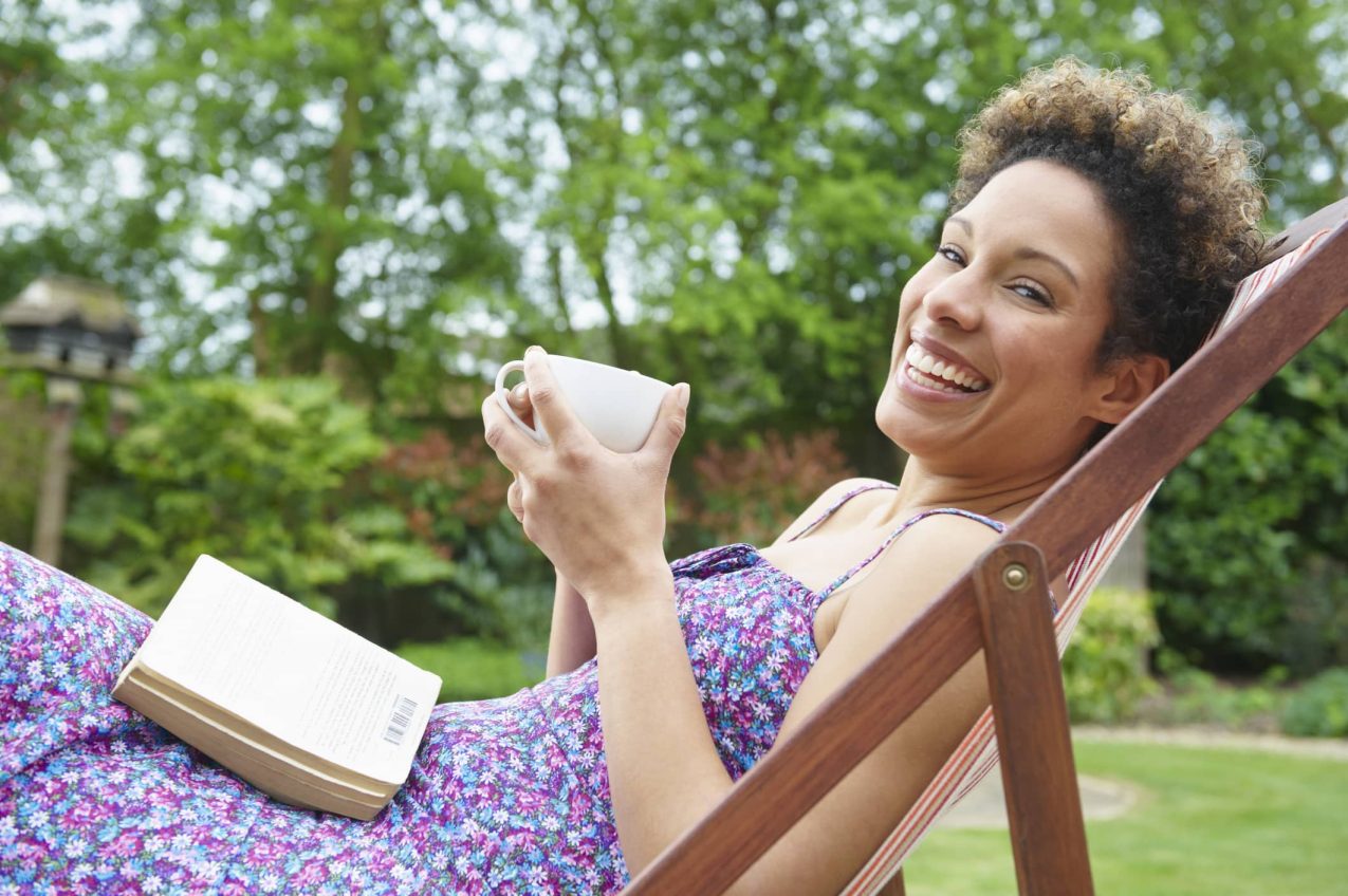 Vrouw In Tuin Op Ligstoelen