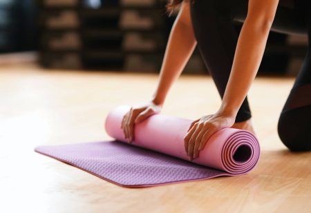 Afvallen Met Yoga: vrouw rolt yogamat op