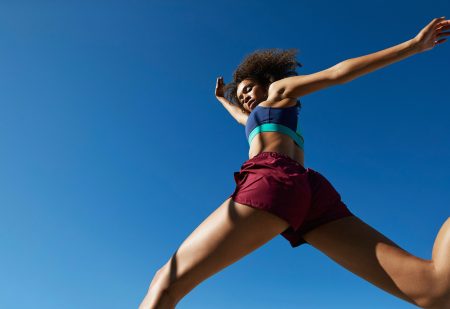 Korte Sportbroekjes: vrouw rent in kort short, met op de achtergrond blauwe lucht