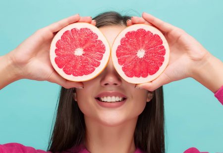 Vitamine C Voor Je Huid: Mooie vrouw met grapefruit in haar handen