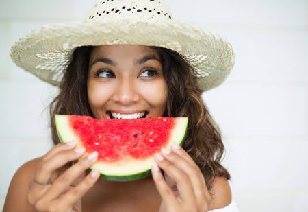 Gezondste Fruit: vrouw neemt hap van een watermeloen, witte achtergrond