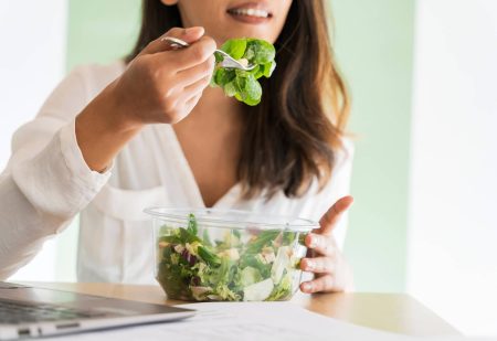 vrouw zit aan tafel en eet een gezonde lunch