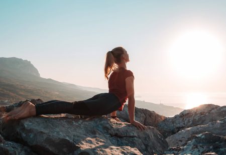 Jonge vrouw beoefent yoga cobra asana voor een slankere taille. Kalmte en ontspanning van mensen op de achtergrond van een berglandschap in de zon