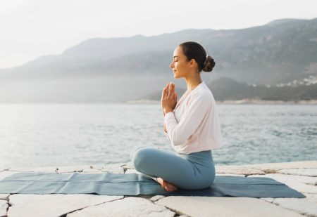 Ochtend Meditatie: Jonge vrouw mediteert buiten aan zee.