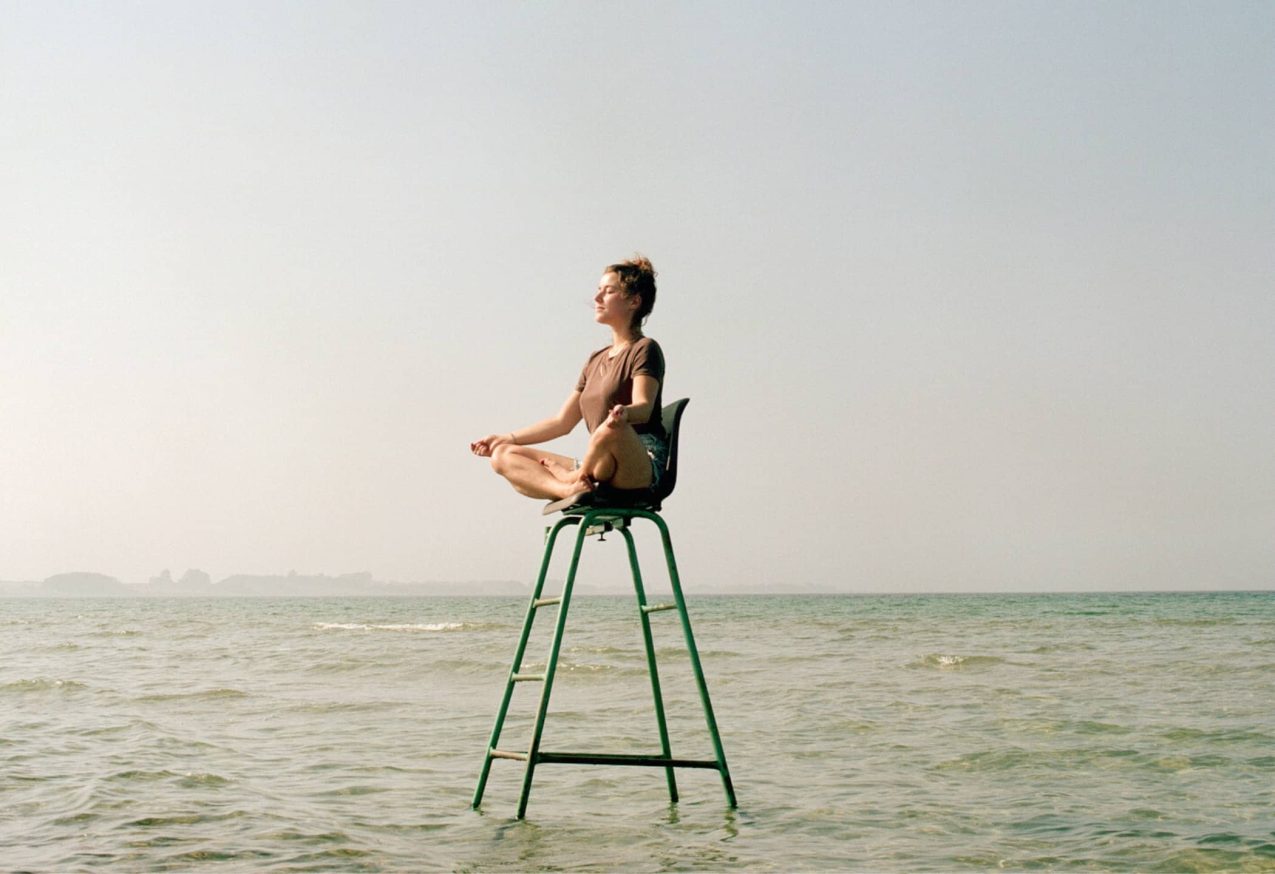 vrouw doet stoel yoga op een hoge stoel in zee