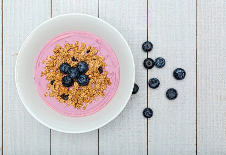 Gezond Ontbijt: Een kom bosbessen yoghurt gemengd met muesli op een rustieke houten achtergrond