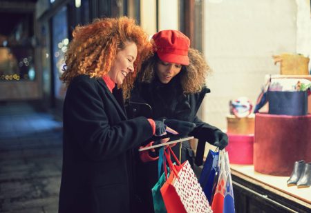 Vrouwen shoppen en een vrouw laat op haar Ipad de Roze Trui Van Hema zien