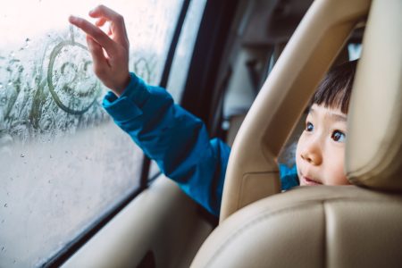 Lovely Cheerful Girl Drawing On Condensed Car Window With Finger While Travelling In Car